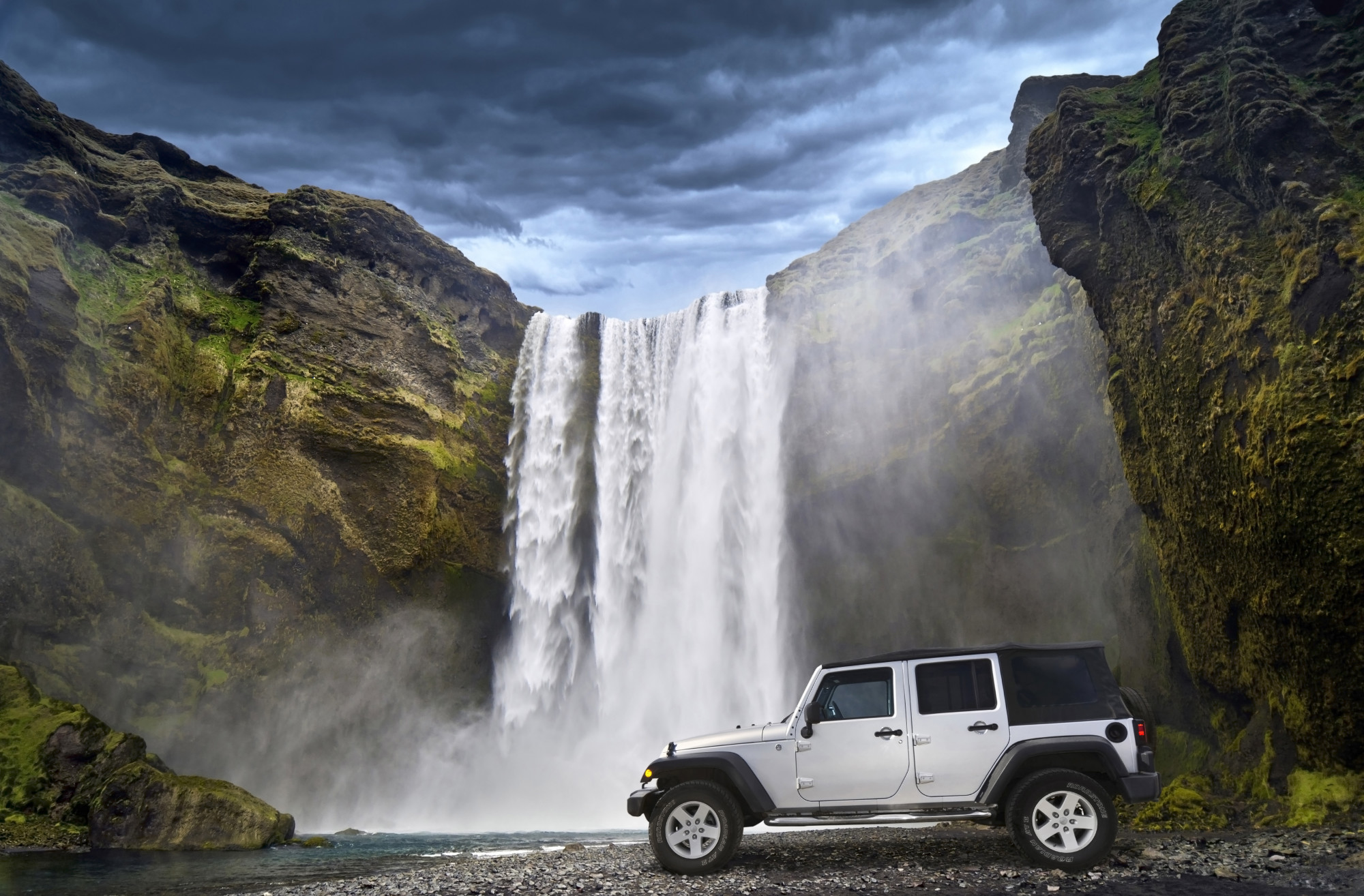 jeep on rugged road near waterfall