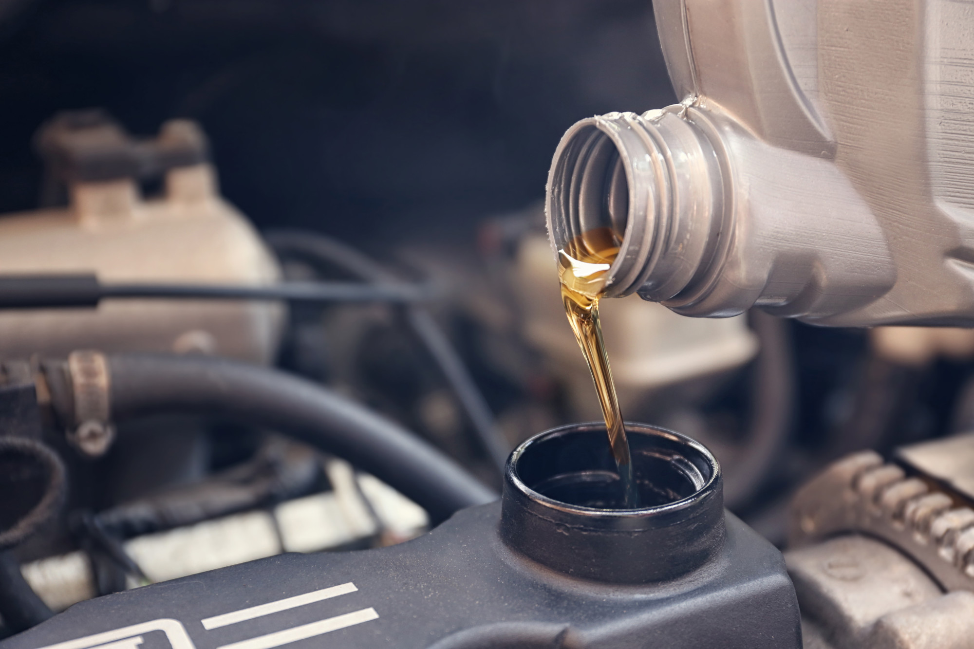 person pouring motor oil into car